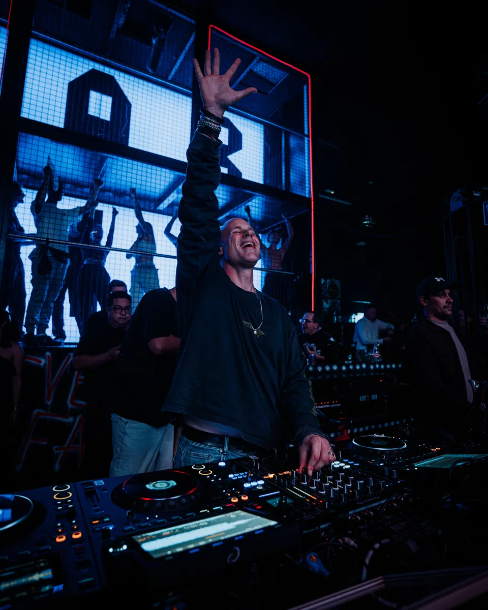 DJ am Mischpult mit erhobener Hand
